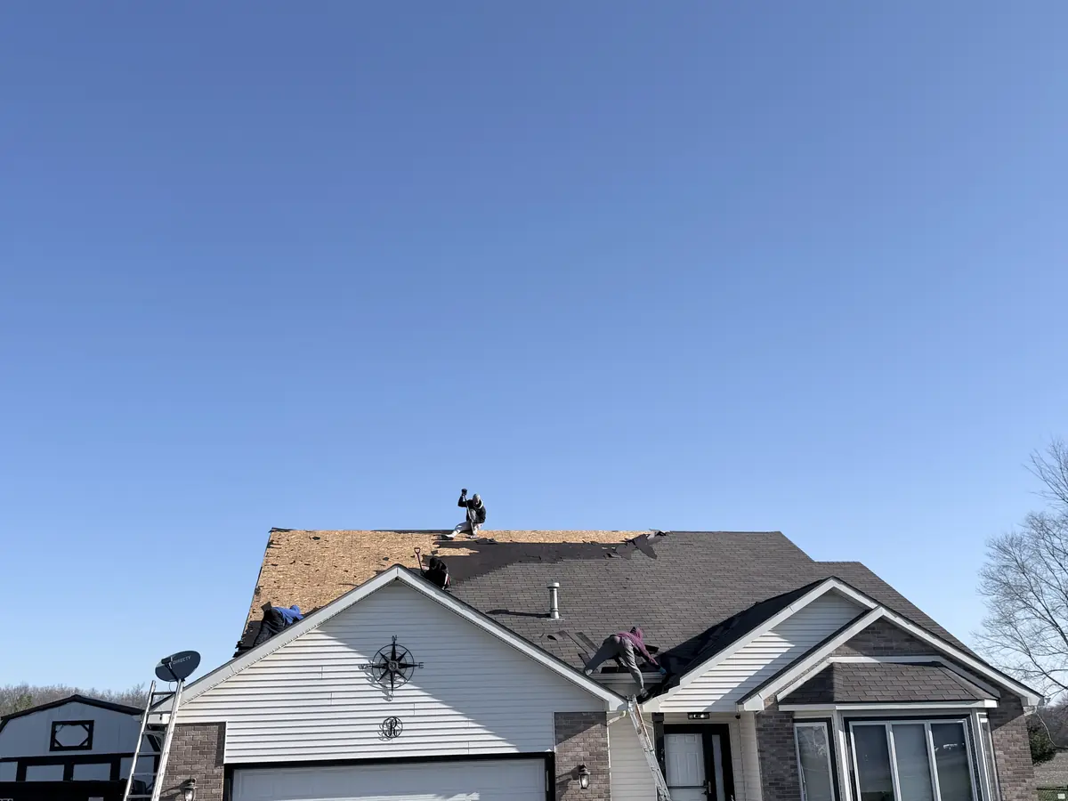 Roof removal in progress with shingles being stripped during a roofing tear-off