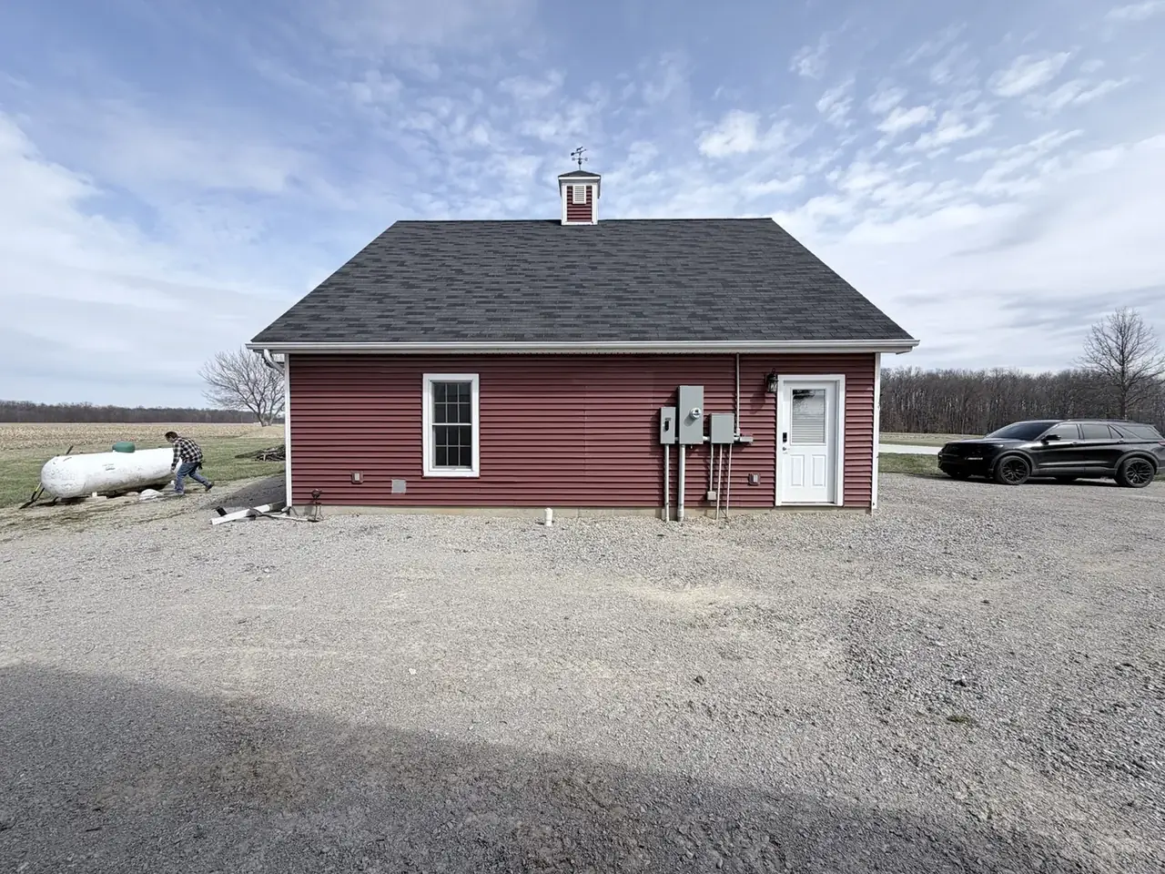 Dark asphalt-shingle roof on a red outbuilding with a cupola