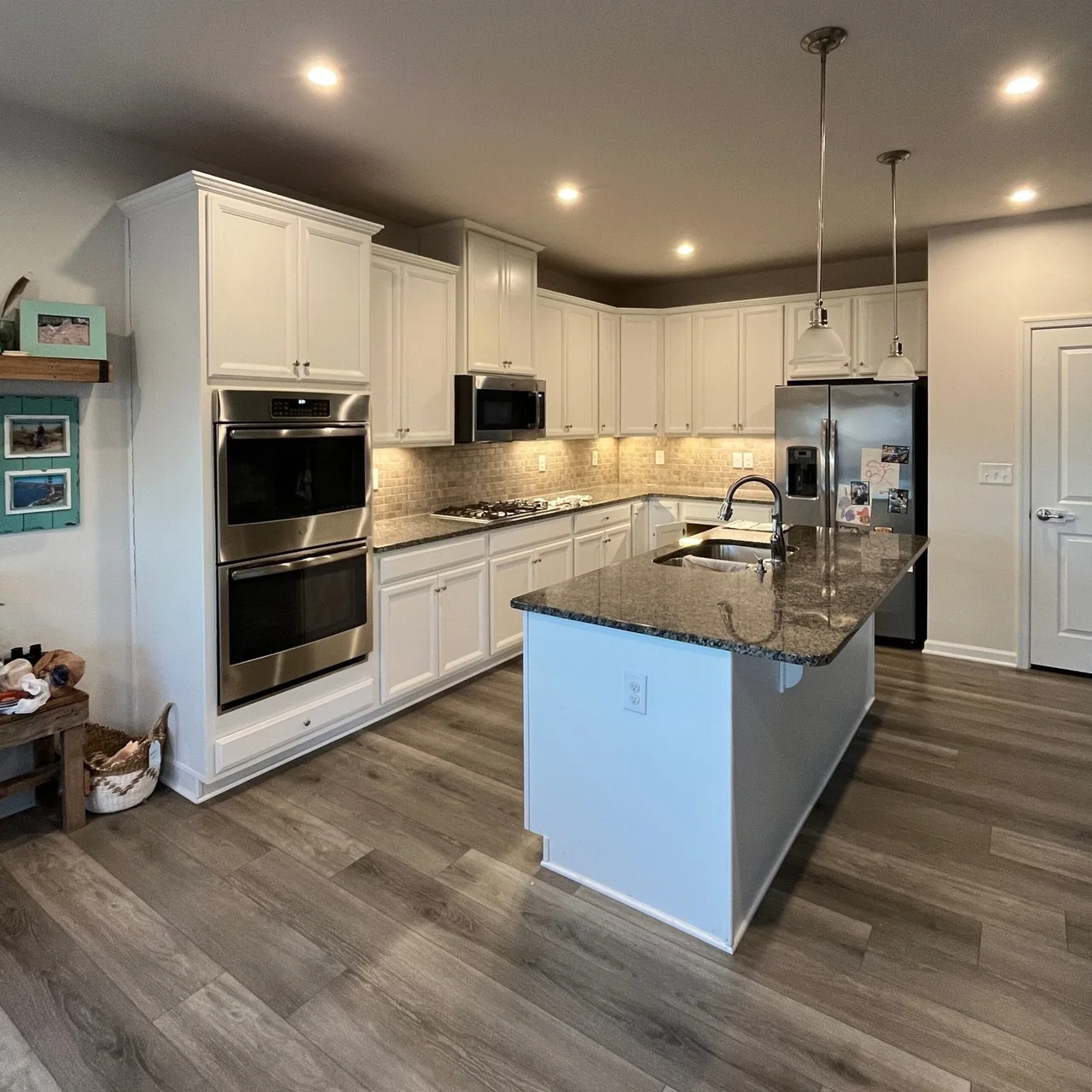 Completed kitchen remodel with white cabinetry, granite countertops, and center island